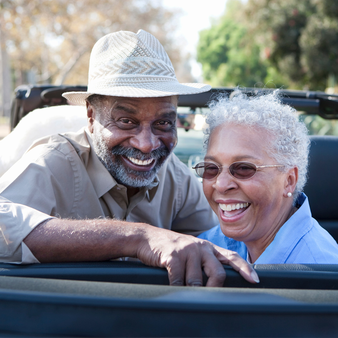 Older couple smiling in car about to take road trip