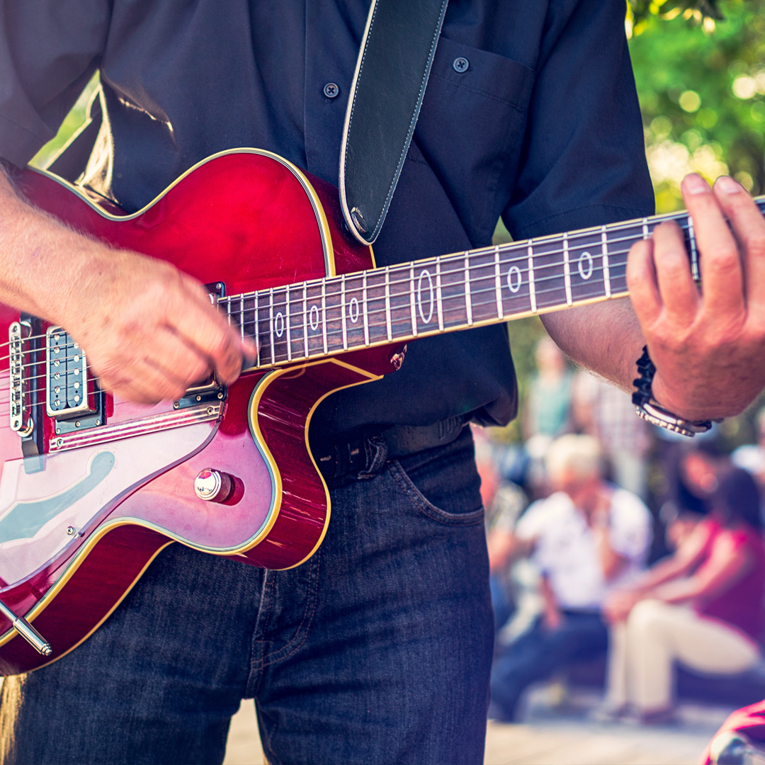 Man onstage playing a guitar at outdoor concert